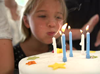 stock-footage-little-girl-blows-out-candles-on-birthday-cake-at-party-slow-motion-sequence